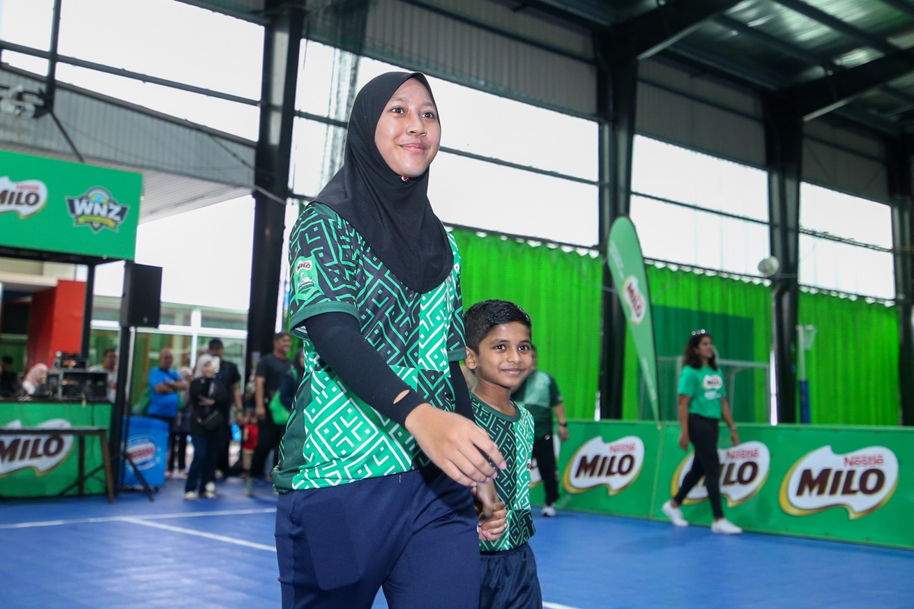 Dhiya Addin and a young participant entering the court together