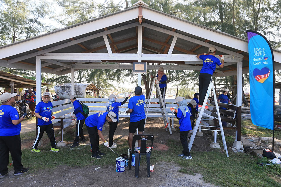 Nestlé volunteers help construct and paint a fishing hut at Pantai Tok Jembal